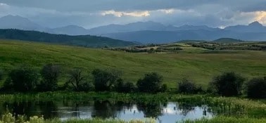 Alberta prairie valley with pond and mountain backdrop